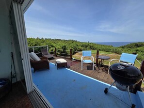 A balcony with outdoor furniture, a grill, and a view of the ocean. - Bluecove Hideaway Relaxing Retreat - Guarida Azul 3BR  Private Pool + Ocean View (Quebradillas)