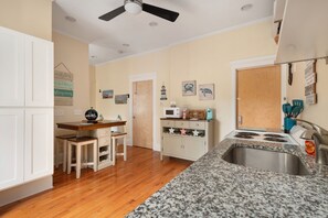A kitchen with wooden flooring, white cabinets, a granite countertop, a stove, and a sink. - Downtown Bristol Studio Near Ferry & Waterfront (Bristol)