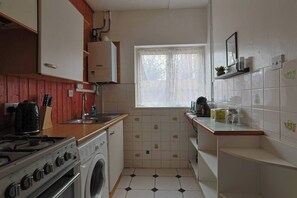 Eine kompakte Küche mit Gasherd, Waschmaschine, Spüle und einem Fenster mit Blick.