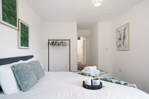 Una habitación de hotel con una cama, un armario, un espejo y obras de arte en las paredes.