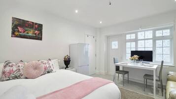 A bedroom with a bed, a desk, and a television.