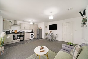 Una cocina moderna con electrodomésticos integrados, un comedor con mesa y sillas, y una sala de estar con sofá y mesa de centro.