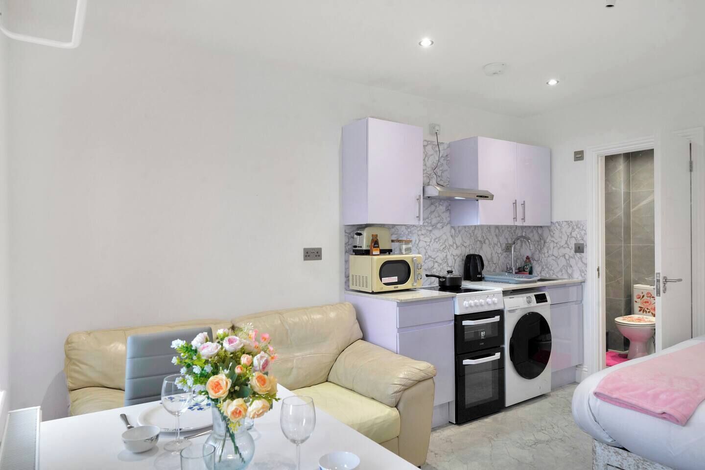 A compact living space with a kitchenette, a dining area, and a bedroom.
