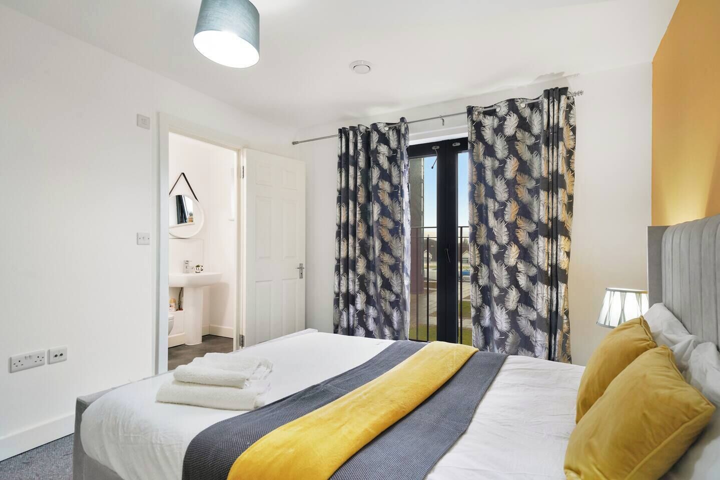 Una camera d'albergo con un letto, un comodino, una lampada e vista all'esterno.