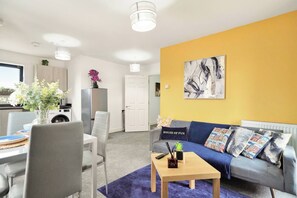 Uma sala de estar moderna com um sofá, uma mesa de centro e um espaço de jantar com cadeiras e uma mesa.