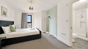 Quarto de hotel com cama, chuveiro e vista para a rua.