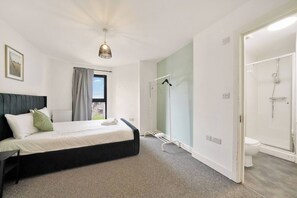 A hotel room with a bed, a shower, and a view of the street.