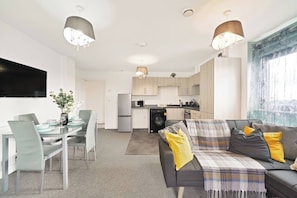 A modern apartment with a dining area, kitchen, and living room.