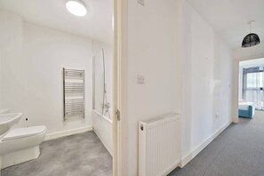 A modern bathroom with a toilet, a towel rack, and a shower enclosure. - Heathrow Gateway Apartments with Private Parking17 (Colnbrook)