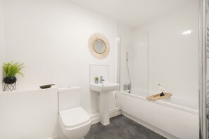 A modern bathroom with a toilet, sink, and shower. - Heathrow Gateway Apartments with Private Parking35 (Colnbrook)