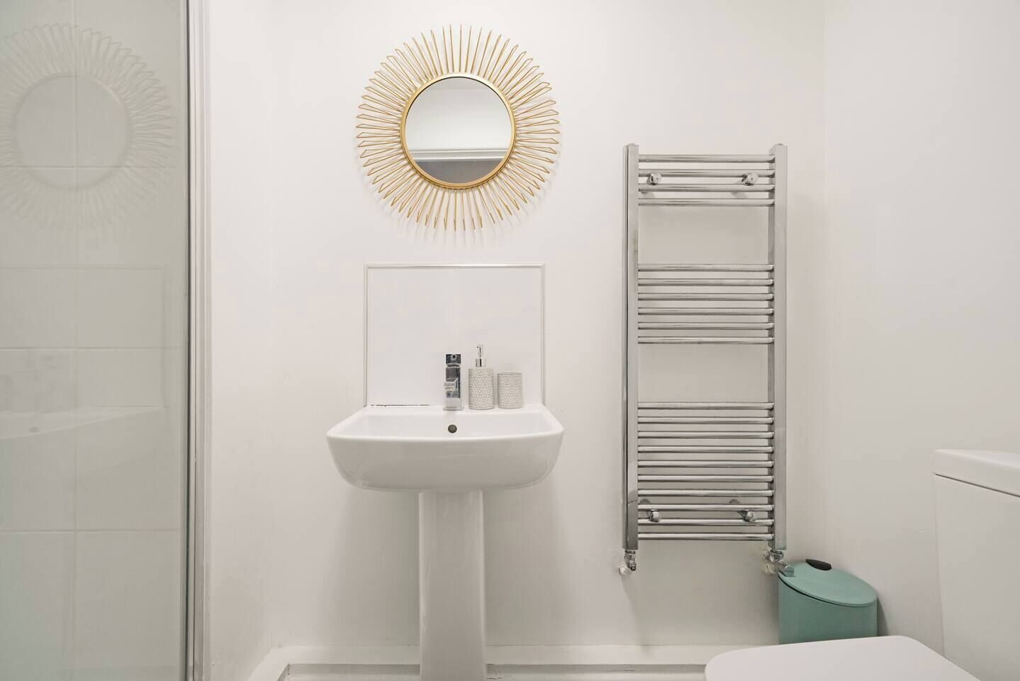 A bathroom with a white sink, a mirror, and a towel rack.