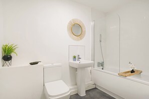 A modern bathroom with a toilet, sink, and shower. - Heathrow Gateway Apartments with Private Parking35 (Harlington)