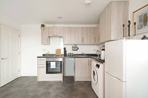 A compact kitchen with a built-in oven, microwave, and dishwasher. - Heathrow Gateway Apartments with Private Parking35 (Harlington)