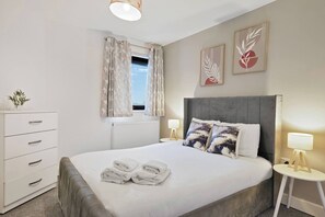 Een hotelkamer met een bed, nachtkastjes, een dressoir en kunst aan de muren.