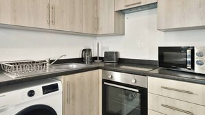 Cozinha compacta com máquina de lavar, micro-ondas e torradeira.