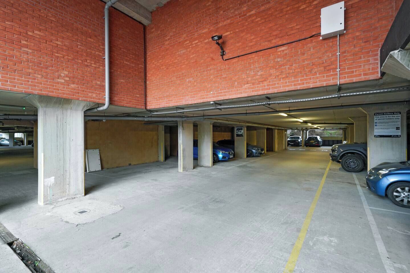 A multi-level parking garage with concrete floors and brick walls.