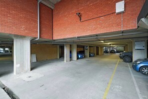 A multi-level parking garage with concrete floors and brick walls. - Heathrow Gateway Apartments with Private Parking13 (London)