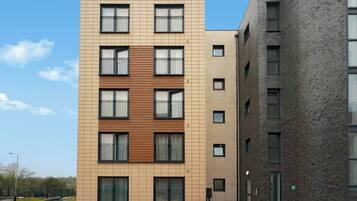 A multi-story residential building with a modern design, featuring a combination of brick and panel facades, large windows, and balconies.