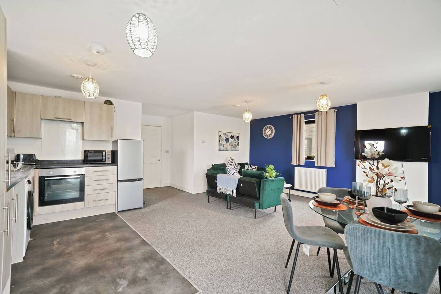 A modern kitchen with built-in appliances, a dining area with a table and chairs, and a living space with a sofa and decorative items.