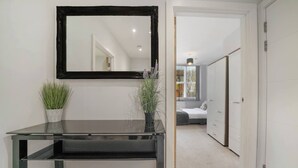 A modern bathroom with a black vanity, a mirror, and two potted plants. - Stylish 1BR Near Heathrow & Elizabeth Line 8 (London)