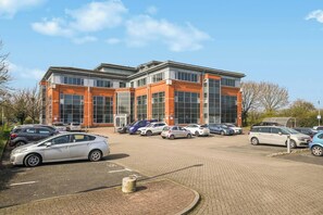 A modern building with a parking lot in front. - Stylish 1BR Near Heathrow & Elizabeth Line 8 (London)