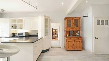 A modern kitchen with white cabinetry, a central island, and a wooden cabinet with glass doors.