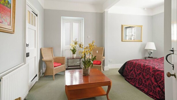 Une chambre d’hôtel avec un lit, deux chaises, une table et une fenêtre.