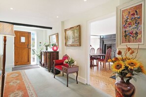 A spacious living room with a fireplace, a dining area with wooden chairs, and a hallway leading to a wooden door. - 16th Century manor house | 6BR | Private Grounds (Harlington)