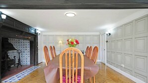 Un coin repas avec une table et des chaises en bois, un vase de fleurs et un tapis à motifs.