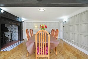 A dining area with a wooden table and chairs, a vase with flowers, and a patterned rug. - 16th Century manor house | 6BR | Private Grounds (Harlington)