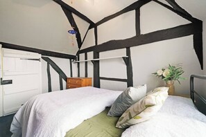 A bedroom with a bed, a dresser, a door, and a vase with flowers. - 16th Century manor house | 6BR | Private Grounds (Harlington)
