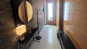 Un vestíbulo de hotel con pared de piedra, un espejo redondo, un banco y una pared revestida de madera.