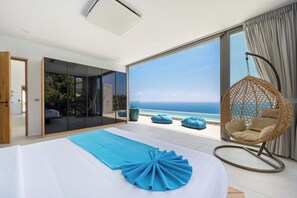 Ein Schlafzimmer mit einem großen Bett, einem Hängestuhl und Blick auf den Ozean.