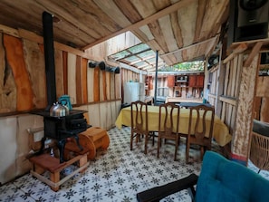 Ein rustikales Zimmer aus Holz mit Tisch, Stühlen, einem Ofen und einem gemusterten Boden.
