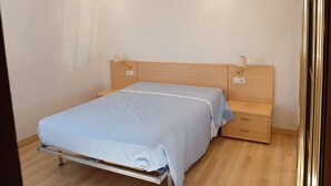 Ett sovrum med en säng, sängbord, ett litet bord och en vägglampa.