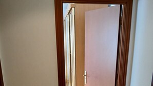 En hall med en trädörr, ett klinkergolv och en dörrmatta med ett trädmotiv.