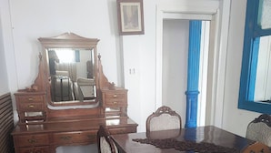 A dining area with a wooden table, chairs, a mirror, and a dresser. - Historical House in Alsancak (Izmir)