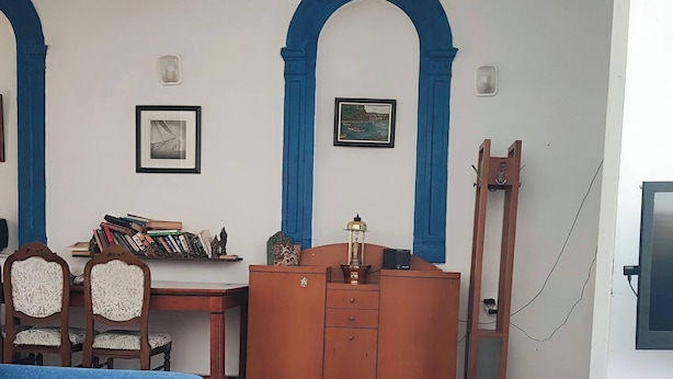 A room with a blue sofa, a wooden desk with books, a lamp, and a cabinet. - Historical House in Alsancak (Izmir)