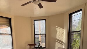 Ein Wohnzimmer mit Deckenventilator, einem beigen Sofa, einem Holztisch und einem gemusterten Teppich.