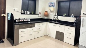Una cucina moderna con piano cottura a gas, mobili bianchi, ripiani neri e un'ampia finestra.