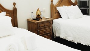 Et hotelværelse med to senge, trægavle, et natbord med lampe og et klædeskab.