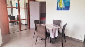 Ein Essbereich mit Korbstühlen und einem Tisch, einer Schiebetür und einem Bild an der Wand.