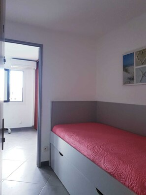 Ein Schlafzimmer mit einem Bett, einer Tür zu einem anderen Raum und einem Wandbild.