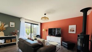 Een woonkamer met een bank, een televisie, een open haard en een raam met gordijnen.