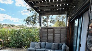 Een overdekt terras met rieten meubels, een bank en een bijzettafeltje.