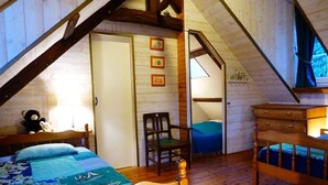 Un dormitorio acogedor en el ático con cama de madera, una silla, un aparador y un escritorio pequeño.
