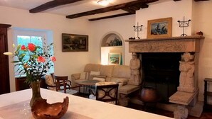 Una habitación con chimenea, una mesa con un jarrón de flores, un sofá y un cuadro en la pared.