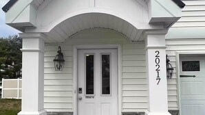 Ein Haus mit einer weißen Haustür, Steinpfeilern und der Hausnummer 20217 am rechten Pfeiler.