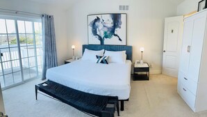 Ein Schlafzimmer mit einem großen Bett, einer Bank, einem Nachttisch, einem Kleiderschrank und einem Gemälde an der Wand.