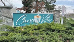Schild für 'Canal RV Villas' mit einer Steinmauer und dichtem Buschwerk im Vordergrund.